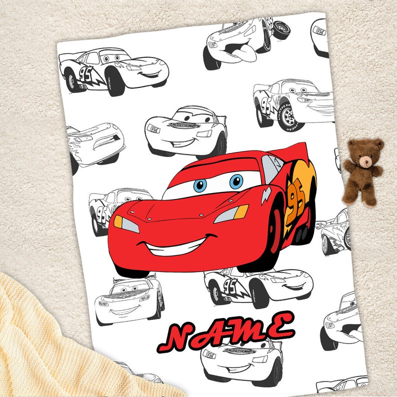May include: A white blanket featuring a repeating pattern of black and white line art of race cars, with one large, central, full-color red race car character with blue eyes and the number 95 on its side. The word NAME is printed in red.