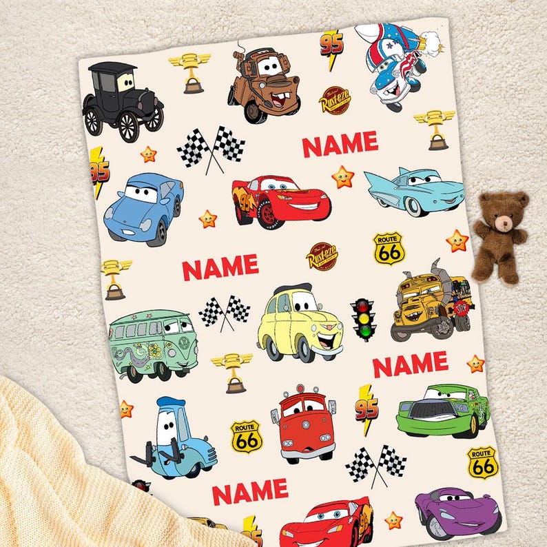 May include: A white and red Cars themed blanket with a variety of characters including Lightning McQueen, Mater, and the tow truck. The blanket has the text "NAME" repeated four times.