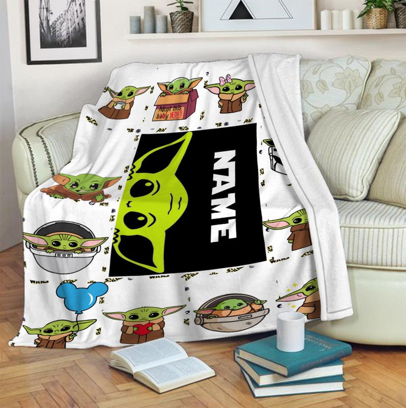 May include: A white fleece blanket featuring a repeating pattern of green alien characters in various poses, including holding a blue balloon, a red heart, and sitting in a pod. A large black rectangular center panel displays the text NAME.