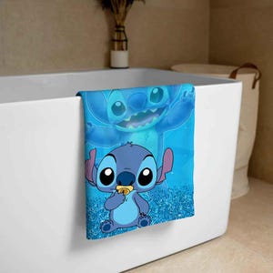 Puede incluir: Una toalla de ba&ntilde;o azul con un fondo azul brillante que presenta a Stitch, un personaje alien&iacute;gena azul de la pel&iacute;cula de Disney Lilo & Stitch. Stitch se muestra en dos poses, una con una expresi&oacute;n juguetona y la otra con una expresi&oacute;n m&aacute;s seria.
