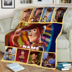 May include: A rectangular fleece blanket featuring multiple panels of the character Woody from Toy Story. The design includes a large central image of Woody tipping his hat with the word NAME printed below, surrounded by seven smaller panels.