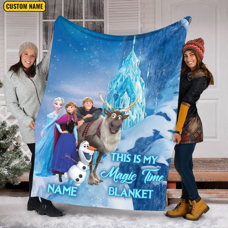 May include: A rectangular fleece blanket featuring a blue winter scene with Elsa, Anna, Kristoff, Sven, and Olaf. The text reads "THIS IS MY MAGIC TIME BLANKET" and includes a placeholder for a custom name. The background shows an ice castle.