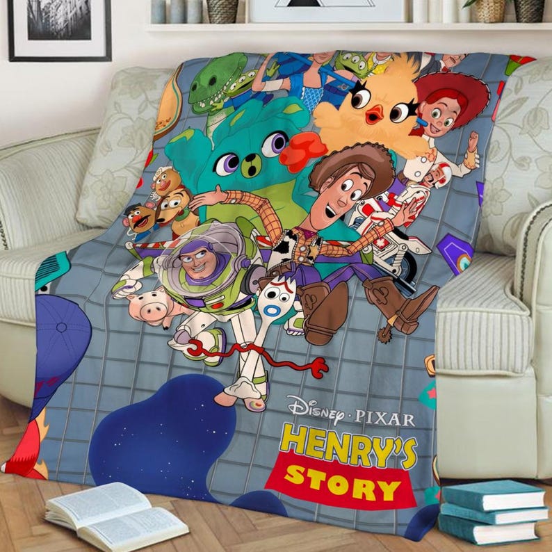 K&ouml;nnte beinhalten: Eine bunte Fleece-Decke mit Figuren aus dem Toy Story-Franchise, darunter Woody, Buzz Lightyear und Jessie. Die Decke hat einen blauen Hintergrund mit einem Fliesenmuster und den Text "Disney Pixar Henry's Story".