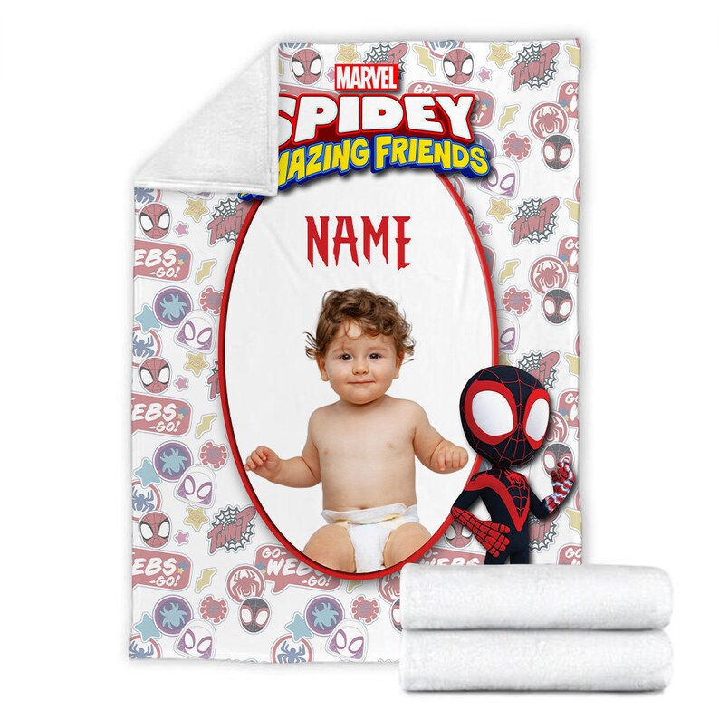 May include: A white fleece blanket featuring a Marvel Spidey and His Amazing Friends pattern with red, blue, and yellow graphics. The center has a large oval frame for a photo, the text NAME, and a cartoon character of Miles Morales in a suit.