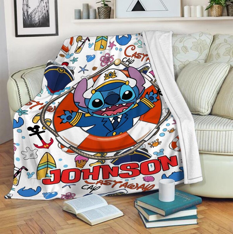 May include: A white fleece blanket with a colourful cartoon design featuring Stitch from Lilo & Stitch. Stitch is wearing a captain's hat and life preserver. The blanket has a white background with blue, red, yellow and green accents. The text "JOHNSON" is written in red letters on the blanket.
