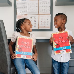 Two kindergarten age children are holding their personalized preschool workbooks