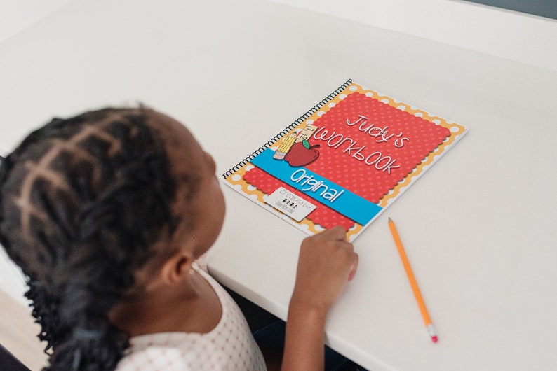 Child working on their personalized workbook. The child is filling out the calendar page and tracing their name.