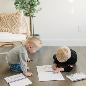 two toddler boys coloring some color books