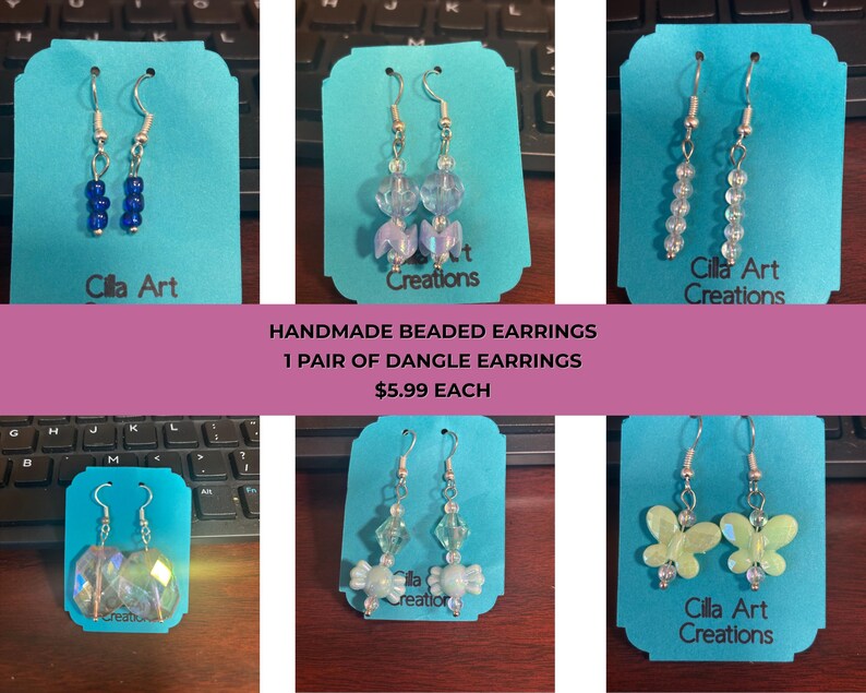 May include: A collection of handmade beaded dangle earrings displayed on teal cards. The earrings feature various designs, including blue beads, clear beads, and butterfly shapes. The text "Cilla Art Creations" is visible on some cards.