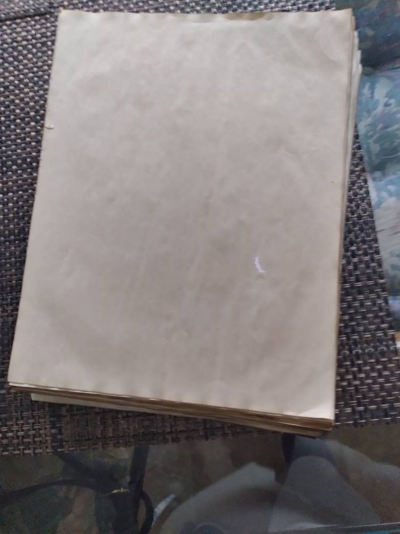 K&ouml;nnte beinhalten: Ein Stapel gealterter, cremefarbener Papierbl&auml;tter. Das Papier hat eine leicht strukturierte Oberfl&auml;che und weist Gebrauchsspuren auf, mit subtilen Verf&auml;rbungen und Knitterfalten. Die Kanten des Papiers sind sichtbar, was auf einen betr&auml;chtlichen Stapel hindeutet.