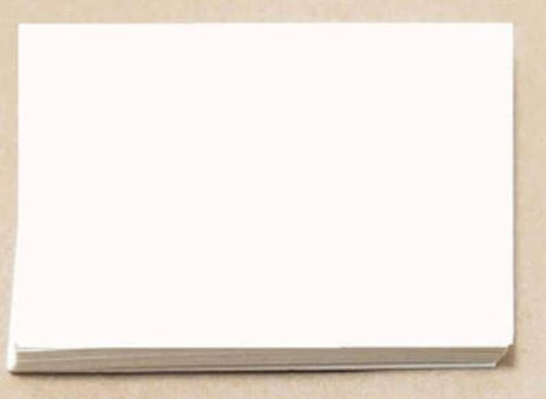 May include: A stack of blank white paper, likely for writing or printing. The paper is neatly stacked, with a clean, crisp appearance. The background is a neutral tan color.