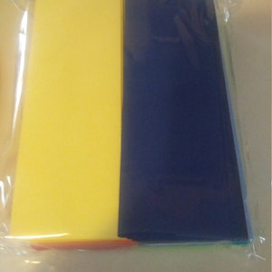K&ouml;nnte beinhalten: Eine Packung mit zwei rechteckigen Bl&auml;ttern, eines gelb und eines marineblau. Die Bl&auml;tter sind in klarem Kunststoff verpackt. Ein d&uuml;nnes orangefarbenes Blatt ist unten in der Packung sichtbar.