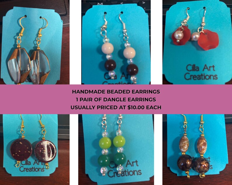 May include: Handmade beaded dangle earrings in various designs. The earrings feature gold-tone hooks and a variety of beads in colors like clear, brown, red, green, and brown. Each pair is displayed on a blue card with the text "Cilla Art Creations".