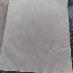 K&ouml;nnte beinhalten: Ein Stapel gealterter, cremefarbener Papierb&ouml;gen. Das Papier hat eine leicht strukturierte Oberfl&auml;che und einen warmen, Vintage-Ton. Die R&auml;nder des Papiers weisen eine subtile braune Farbe auf, die auf Alterung oder eine spezielle Behandlung hindeutet. Das Papier ist wahrscheinlich f&uuml;r Bastelarbeiten oder k&uuml;nstlerische Zwecke bestimmt.