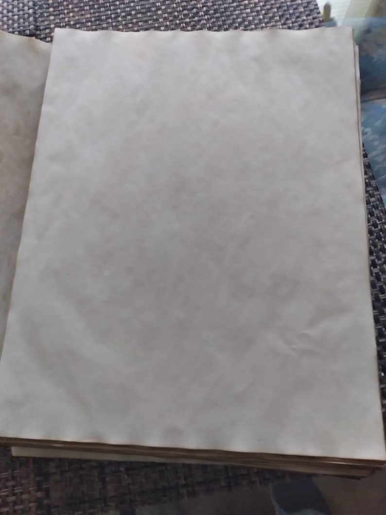 K&ouml;nnte beinhalten: Ein Stapel gealterter, cremefarbener Papierb&ouml;gen. Das Papier hat eine leicht strukturierte Oberfl&auml;che und einen warmen, Vintage-Ton. Die R&auml;nder des Papiers weisen eine subtile braune Farbe auf, die auf Alterung oder eine spezielle Behandlung hindeutet. Das Papier ist wahrscheinlich f&uuml;r Bastelarbeiten oder k&uuml;nstlerische Zwecke bestimmt.