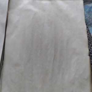 K&ouml;nnte beinhalten: Ein Stapel gealterter, cremefarbener Papierb&ouml;gen. Das Papier hat eine leicht strukturierte Oberfl&auml;che mit subtilen Farbvariationen, und die R&auml;nder weisen ein dunkleres, gealtertes Aussehen auf. Das Papier ist wahrscheinlich f&uuml;r k&uuml;nstlerische oder dekorative Zwecke bestimmt.