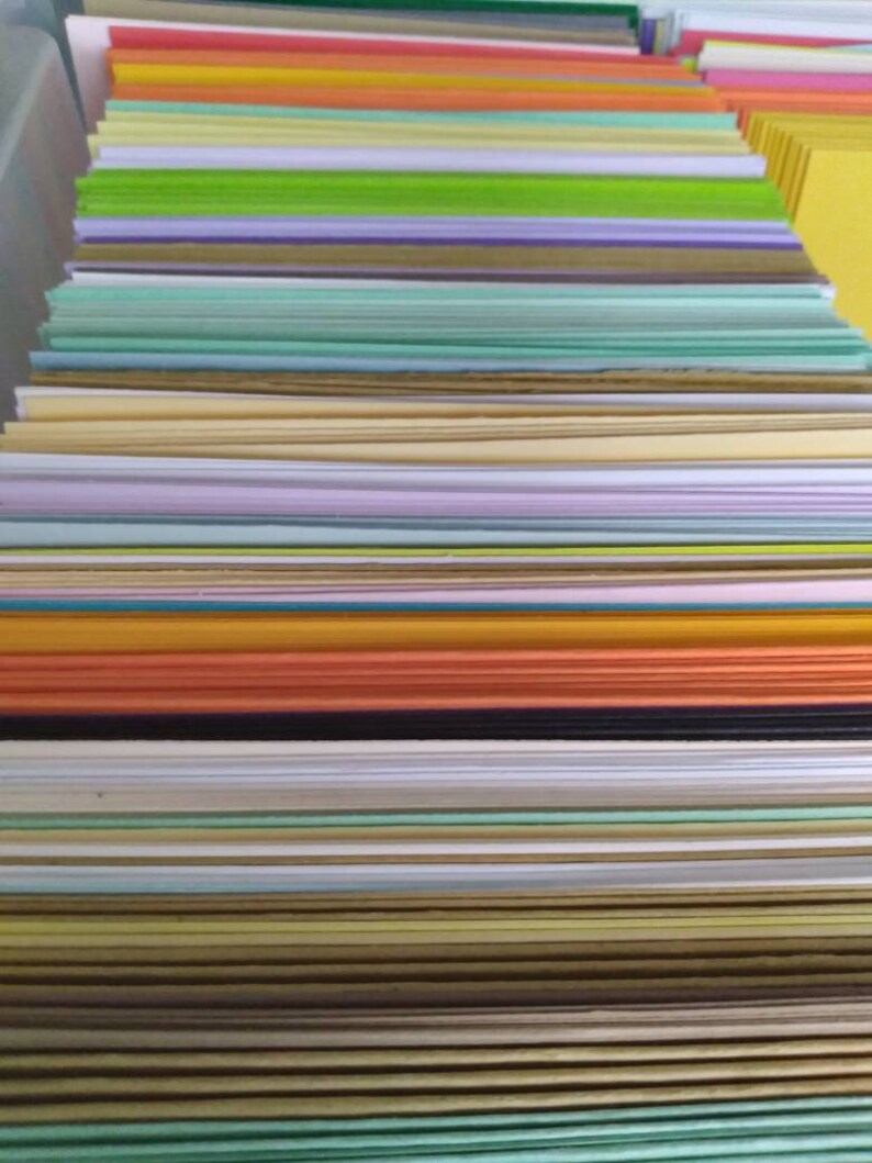 May include: A stack of colorful paper sheets in various hues, including red, orange, green, and purple. The paper is neatly arranged, creating a visually appealing display of stationery supplies. The image showcases a variety of colors and textures.