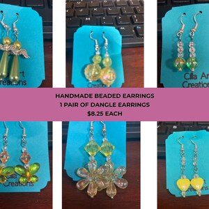 May include: A collection of handmade beaded dangle earrings in various designs. The earrings feature silver hooks and colorful beads, including angel wings, butterflies, and floral shapes. The text "HANDMADE BEADED EARRINGS" is visible.