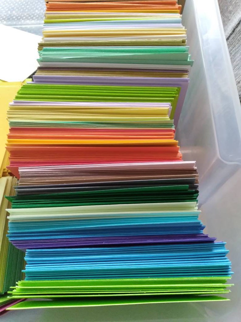 May include: A stack of colorful cardstock paper in various shades, including green, yellow, orange, blue, and purple. The paper is neatly arranged, creating a vibrant and organized display. Ideal for crafting and stationery projects.