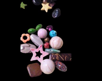 May include: A collection of colorful beads in various shapes and sizes. Includes star, oval, and round beads in shades of pink, green, brown, and blue. Some beads have patterns or textures.