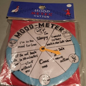 May include: A white and blue mood meter game with a yellow pointer. The game has different options like "I'm in the mood for love", "I'm sleepy", "I would rather watch the late show", "Coax me", "Less talk", "More action".