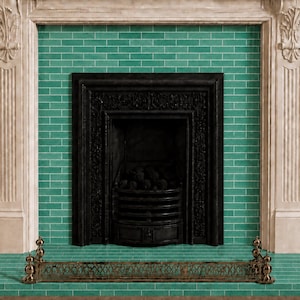 May include: A decorative fireplace with a black cast iron firebox and a green tiled surround. The fireplace is framed by a white mantel with ornate carvings. A brass fire screen sits on the hearth.