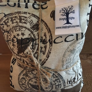 May include: A beige fabric pouch with a brown twine tie. The pouch is decorated with a repeated pattern of brown coffee-themed stamps. The pouch has a white tag attached with the text "Simply Gifts" and a website address.