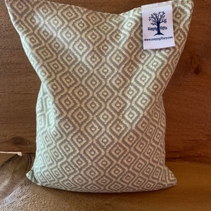 May include: A decorative pillow with a geometric diamond pattern in shades of gray and off-white. The pillow has a tag that reads "Simply Gifts" and the website address.