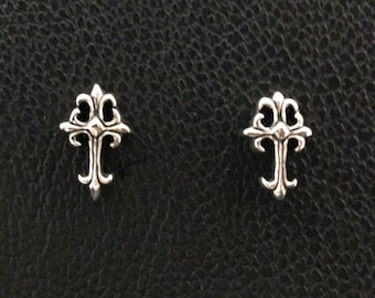 May include: A pair of silver cross earrings with a detailed design.