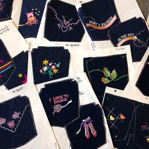 May include: A collection of 10 denim patches with various embroidered designs, including a star, flowers, a rainbow, a ballerina, and tic-tac-toe. The patches are on white cardstock with handwritten numbers.