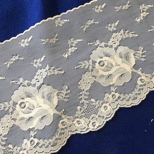 May include: White lace trim with a scalloped edge and floral design. The lace features delicate roses and leaves.