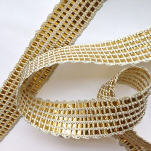 May include: Gold and ivory trim with a square pattern. The trim has a scalloped edge.
