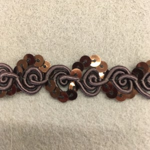 May include: A brown and gold trim with a repeating pattern of swirls and sequins. The trim is made of a soft, flexible material and is perfect for adding a touch of elegance to any project.