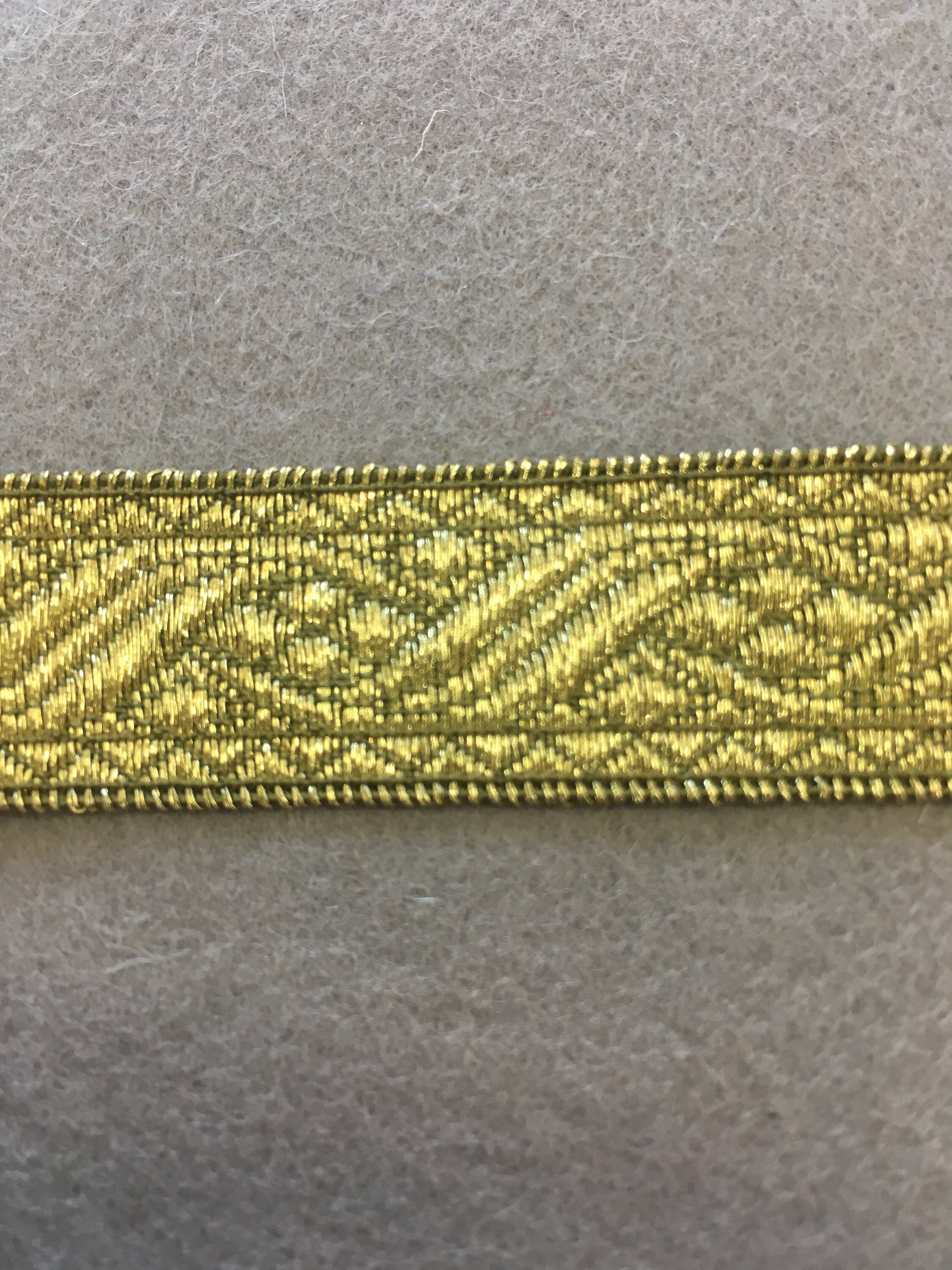Patterned antique gold flat trim with two straight edges. 13/16 wide