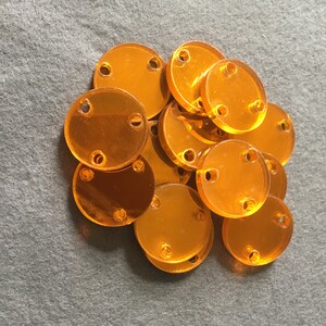 May include: A pile of 15 orange plastic round discs with three holes each.