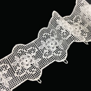 May include: White lace trim with a delicate floral pattern and scalloped edges. The trim has a net-like texture and is perfect for adding a touch of elegance to any project.
