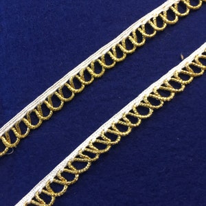 May include: White and gold trim with a looped design. The trim is made of a soft, flexible material and has a subtle shimmer.