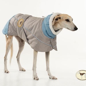 Peut inclure: Un manteau pour chien gris et bleu avec une doublure en polaire. Le manteau a un patch avec le texte "Greyt Sweaters Greyhound and Whippet Suits".