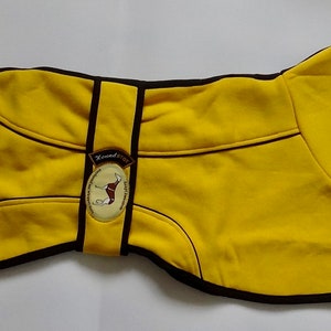 May include: Yellow dog coat with black trim and a brown patch with a dog silhouette and the text "Hound & Co."