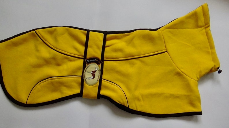 May include: Yellow dog coat with black trim and a brown patch with a dog silhouette and the text "Hound & Co."