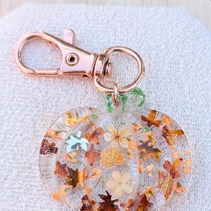 Autumn bag charm, pumpkin bag charm, rose gold coloured clip, pressed flowers pumpkin charm, pumpkin zip charm, fall bag charm, pumpkin with pressed flowers, real flowers bag charm, resin bag charm, pumpkin keyring, pressed flower pumpkin keyring, zip charm, Halloween bag charm, Halloween accessories, autumn accessories, pressed flower pumpkin charm