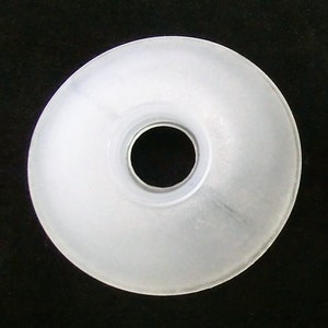 May include: A white plastic washer with a large center hole. The washer is smooth and has a slightly frosted appearance.