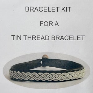 May include: A bracelet kit for a tin thread bracelet. The kit includes a black leather base with a silver thread design.