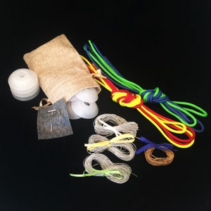 May include: A set of colourful spools of thread with a burlap bag, bobbins, and safety pins. The spools are red, yellow, green, and blue.