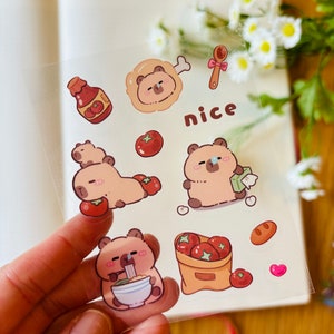 Pu&ograve; includere: Un foglio di adesivi trasparenti con orsi dei cartoni animati con diverse espressioni. Gli adesivi includono un orso che mangia noodles, un orso che tiene un pomodoro, un orso con un bendaggio, un orso con un osso, una bottiglia di ketchup, un sacchetto di pomodori, un cucchiaio, un pezzo di pane, un cuore e la parola "nice".