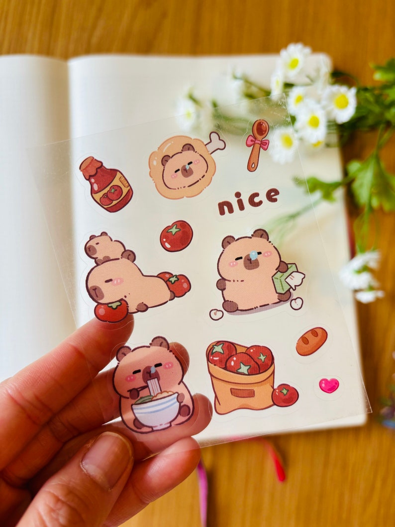 Pu&ograve; includere: Un foglio di adesivi trasparenti con orsi dei cartoni animati con diverse espressioni. Gli adesivi includono un orso che mangia noodles, un orso che tiene un pomodoro, un orso con un bendaggio, un orso con un osso, una bottiglia di ketchup, un sacchetto di pomodori, un cucchiaio, un pezzo di pane, un cuore e la parola "nice".