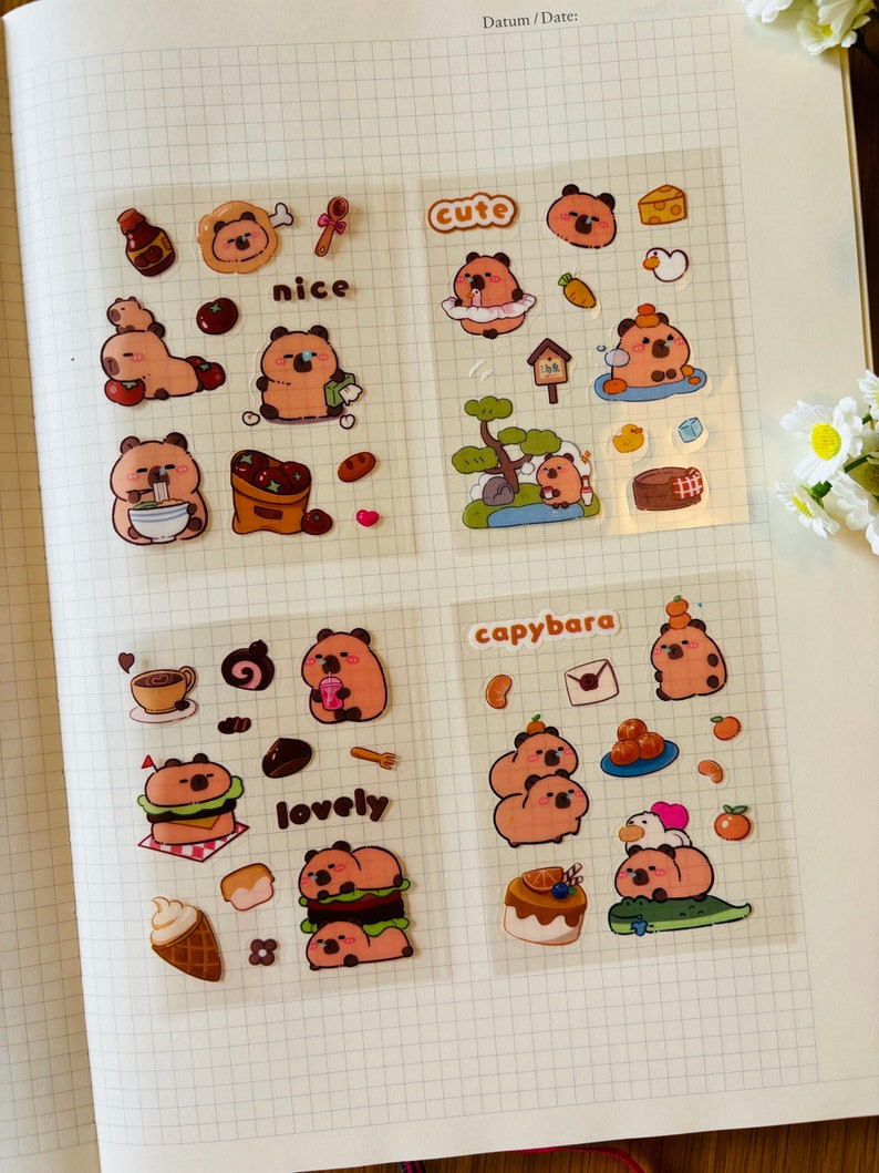 Pu&ograve; includere: Un foglio di adesivi trasparenti con simpatici capibara dei cartoni animati in varie pose e ambientazioni. Gli adesivi includono frasi come "cute", "nice", "lovely" e "capybara".