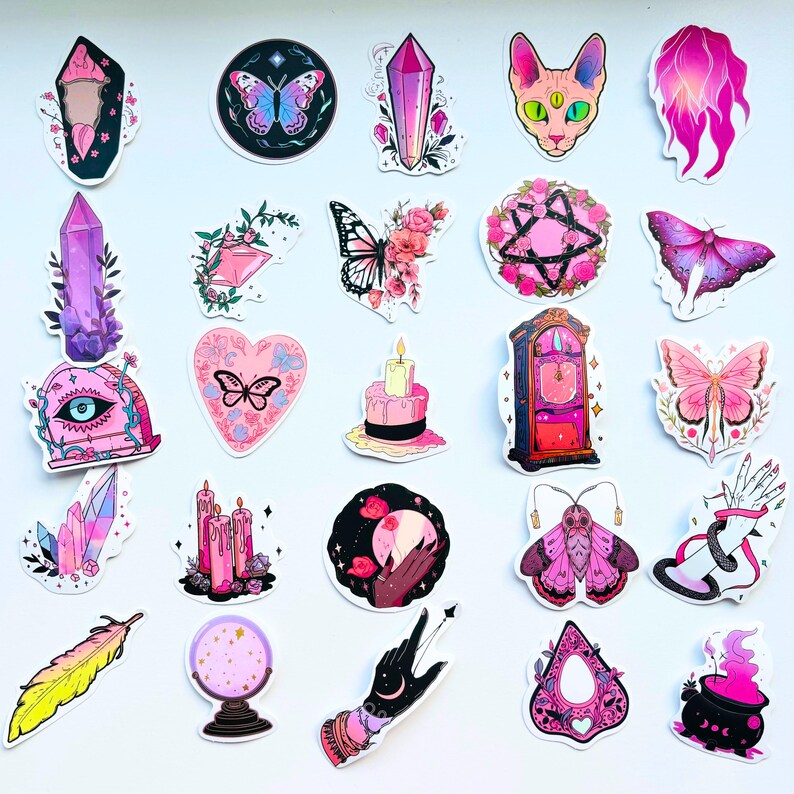 May include: A collection of colorful stickers featuring mystical and witchy designs. The stickers include butterflies, crystals, a cat, a clock, a feather, a fortune-telling ball, and a cauldron. The color palette includes pink, purple, black, and yellow.
