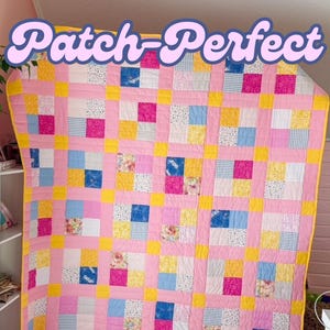 May include: A pink and yellow patchwork quilt with a variety of floral and geometric patterns. The quilt is made up of squares and is stitched together with yellow thread. The quilt is titled "Patch-Perfect" and is by Shelby McCollum.