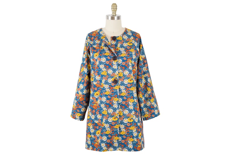 May include: A long-sleeved floral print coat with a button closure. The coat is blue with a floral pattern in shades of orange, yellow, and white.